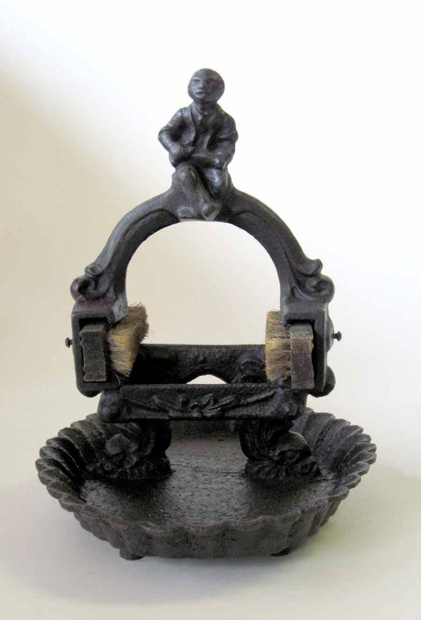 Painted Cast-iron figural shoe scraper, late 19th: Painted Cast-iron figural shoe scraper late 19th century Cast with figure of an African-American man above brushes raised on dolphin supports and oval scalloped base. H: 14 in. L: 12 in.