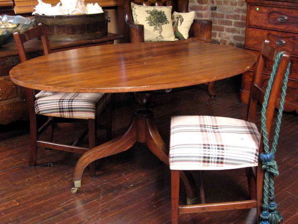 A 19th century mahogany tilt-top table: A 19th century mahogany tilt-top table the oval top above an urn-form standard, raised on a trefoil base upon casters 28 ½ in. high, 54 in. wide, 37 ½ in. deep