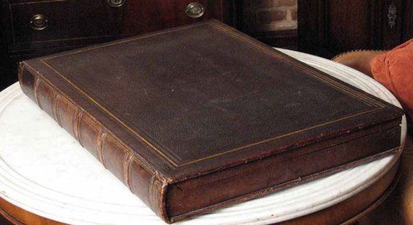 A late 19th/early 20th century leather bound portf: A late 19th/early 20th century leather bound portfolio box modelled as large book, with gilt tooled decoration and opening to reveal a lined fold out interior 24 in. wide, 18 in. deep