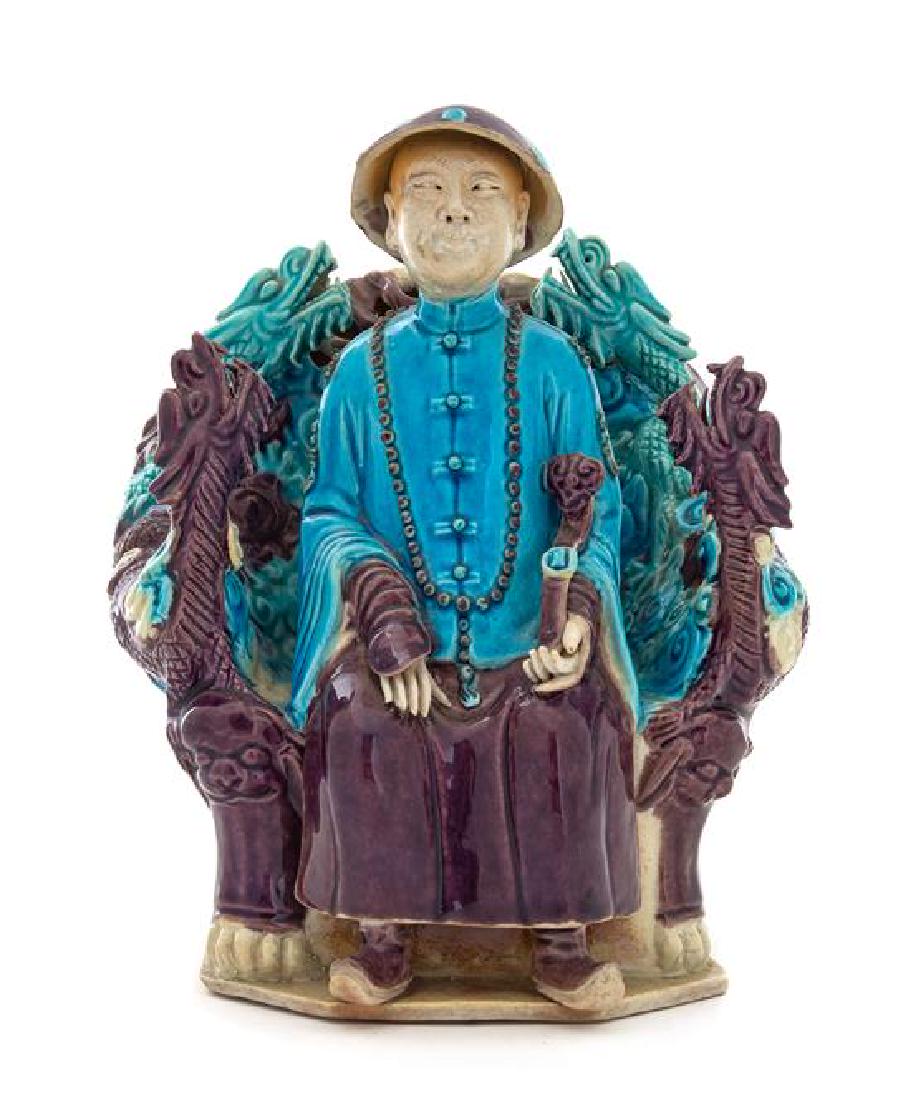 A Turquoise Aubergine Glazed Porcelain Figure of an: A Turquoise Aubergine Glazed Porcelain Figure of an Official 19th century the figure depicted seated in a dragon throne, wearing official's robes with a long court necklace, the left hand holding a sc