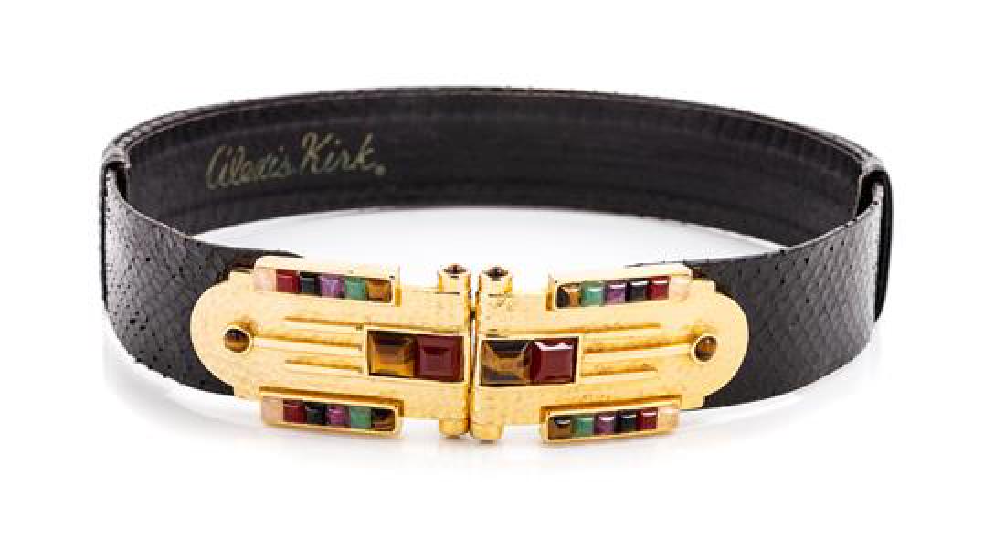 An Alexis Kirk Black Snakeskin Slide Belt, 23" - 36" L: An Alexis Kirk Black Snakeskin Slide Belt, with an inset stone and hammered goldtone buckle and an adjustable strap. Stamped: Alexis Kirk. 23" - 36" L x 1.5" W. Estimate $100-200 Overall very good con