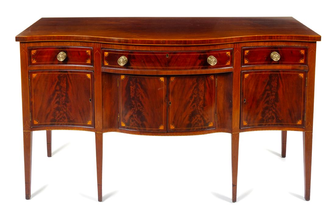 A Federal Style Mahogany Sideboard Height 37 3/4 x: A Federal Style Mahogany Sideboard late 19th/early 20th century the rectangular top of serpentine outline above the conforming case fitted with three aligned drawers and four doors, raised on square t