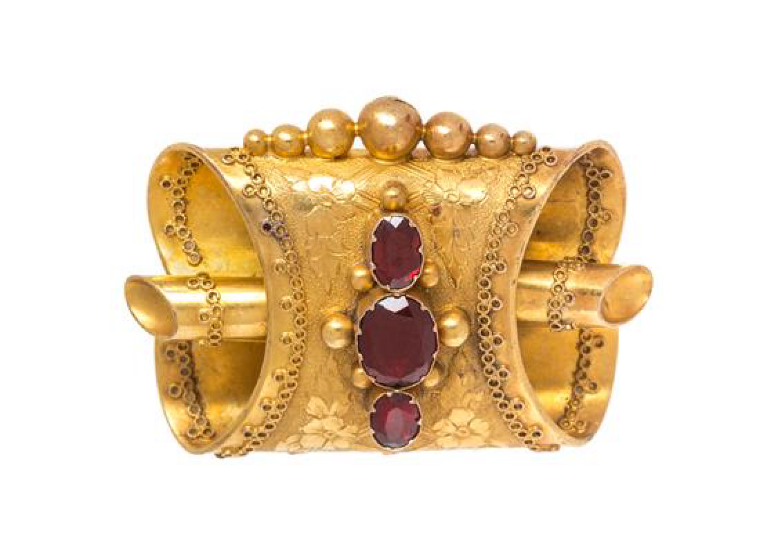 An Etruscan Revival Yellow Gold and Garnet Brooch, 6.50: An Etruscan Revival Yellow Gold and Garnet Brooch, consisting of a scroll design containing one oval shape mixed cut garnet measuring approximately 8.40 x 6.25 mm and two oval shape mixed cut garnet m