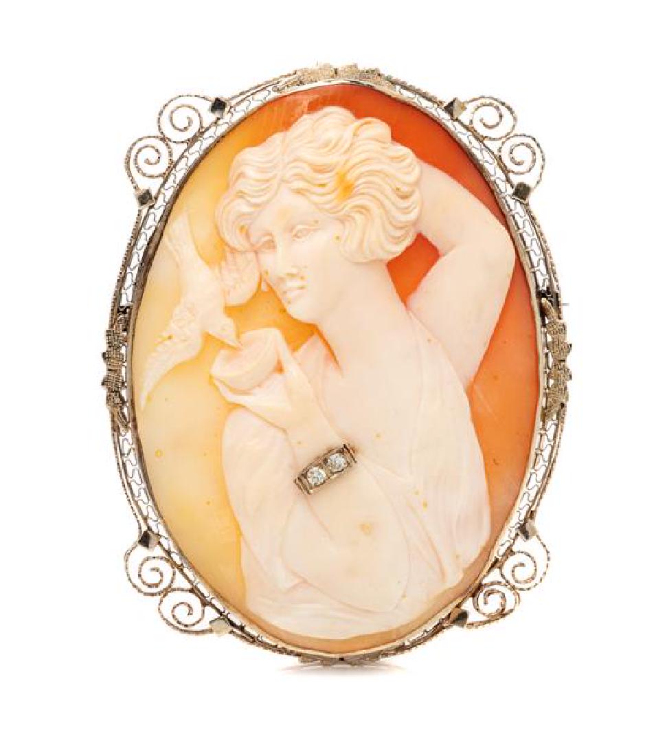 A 14 Karat White Gold, Diamond and Shell Cameo: A 14 Karat White Gold, Diamond and Shell Cameo Pendant/Necklace, containing a shell cameo measuring approximately 58.00 x 43.00 mm carved with the image of a woman feeding a bird and wearing a bracele
