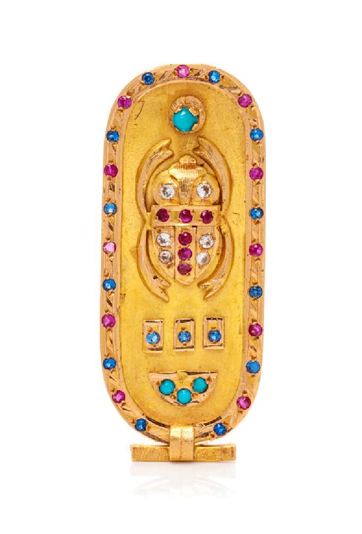 An 18 Karat Rose Gold and Multigem Cartouche Brooch,: An 18 Karat Rose Gold and Multigem Cartouche Brooch, consisting of an applied beetle and abstract Egyptian motifs, containing numerous round mixed cut rubies, four round cabochon cut turquoise, numero