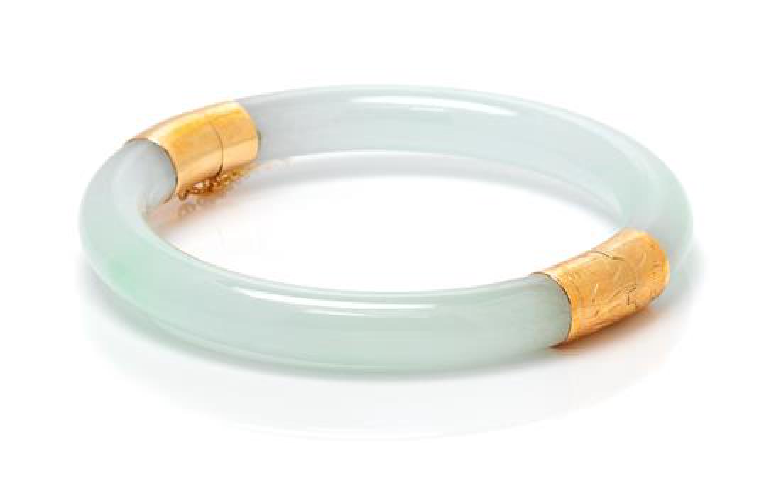 A 14 Karat Yellow Gold and Jade Bangle, 22.00 dwts.: A 14 Karat Yellow Gold and Jade Bangle, consisting of two curved jade sections measuring approximately 7.00 mm wide joined by a yellow gold hinge and clasp with safety chain. Stamp: 14K 585. 22.00 dwt