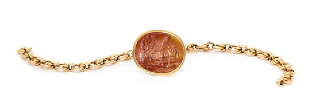 An 18 Karat Yellow Gold and Agate Intaglio Bracelet,: An 18 Karat Yellow Gold and Agate Intaglio Bracelet, containing one oval shape carved agate intaglio measuring approximately 25.00 x 28.00 mm depicting two figures suspended from a round link chain. S