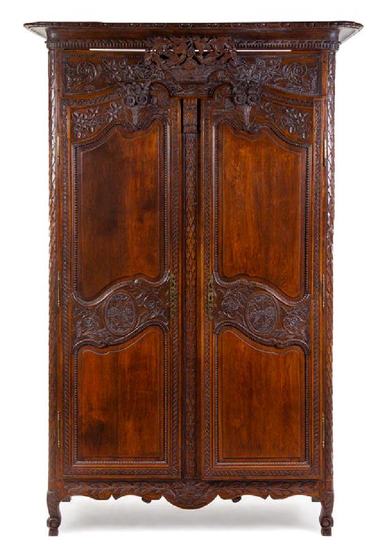 A French Provincial Carved Walnut Armoire Height 87 3/4: A French Provincial Carved Walnut Armoire probably brittany, early 19th century having a cavetto cornice with egg-and-dart and dentiled bands above the frieze carved to show flowering vines in relief 