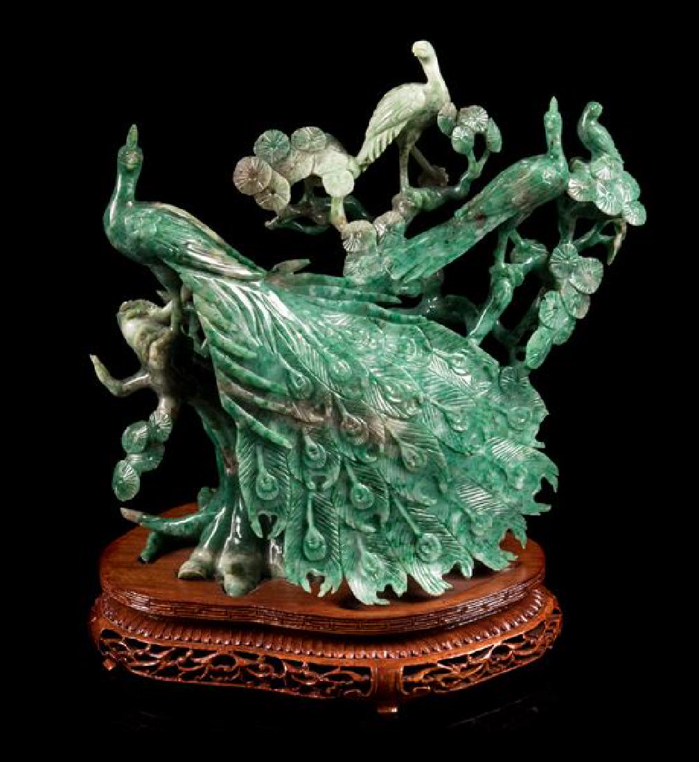 * A Green Jadeite Figural Group of Birds Height 8 1/4: * A Green Jadeite Figural Group of Birds 20th century depicting two peacocks and smaller birds perched on pine trees, raised on a fitted hardwood stand. Height 8 1/4 inches. Estimate $600-800 Property