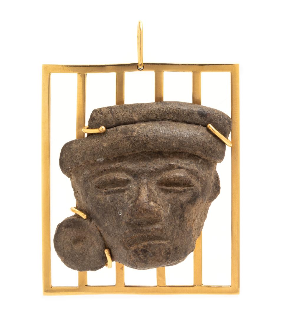 A Yellow Gold and Possibly Pre-Colombian Stone Head: A Yellow Gold and Possibly Pre-Colombian Stone Head Pendant, consisting of a weathered carving of a face mounted on a yellow gold grid-like frame, pendant measures approximately 56.00 x 66.00 excludin
