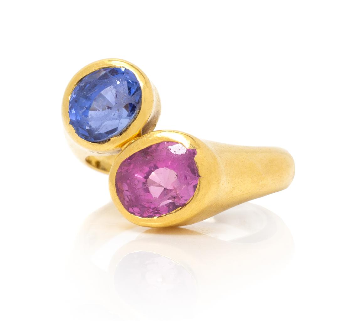 A Yellow Gold, Pink and Blue Sapphire Ring, Angela: A Yellow Gold, Pink and Blue Sapphire Ring, Angela Cummings, consisting of a bypass design, containing one round mixed cut blue sapphire measuring approximately 6.45 x 6.91 x 5.43 mm and one oval mixe