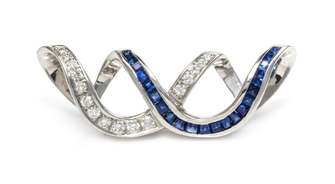 An 18 Karat White Gold, Diamond and Sapphire: An 18 Karat White Gold, Diamond and Sapphire Slide/Enhancer, Charles Krypell, consisting of a ribbon design containing 167 round brilliant cut diamonds weighing approximately 0.24 carat total and 22 c
