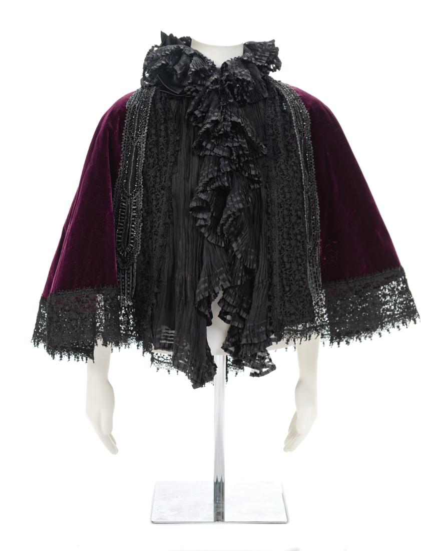A Worth Purple Velvet and Jet Cape, 1890s: A Worth Purple Velvet and Jet Cape, 1890s Purple silk velvet trimmed with black lace and embellished with jet that falls into fringe. A pleated silk chiffon ruffle wraps neckline and extends down the