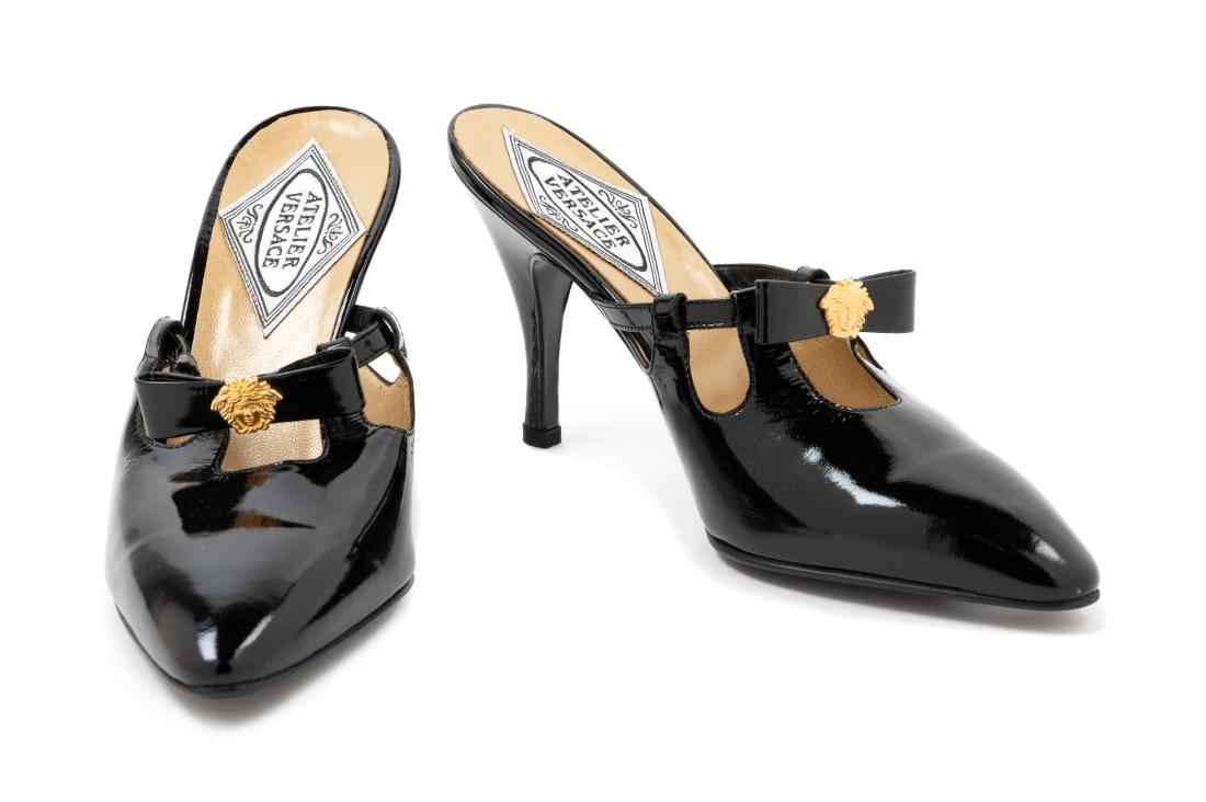 Atelier Versace Black Patent Mules, 1990s: Atelier Versace Black Patent Mules, 1990s With black bow and goldtone medusa. Size 38. Together with a box. Label: Atelier Versace Estimate $60-80