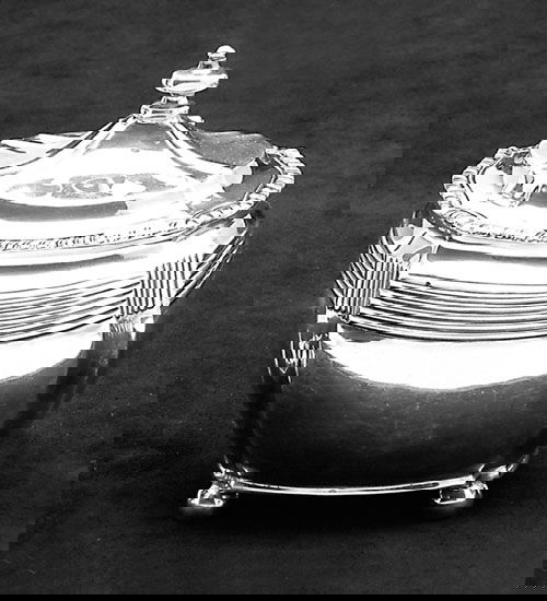 AN ENGLISH SILVER TEA CADDY: London 1893, Charles Stuart Harris Oblong with concave corners, the reeded neck below a hinged domed conforming lid and gadrooned rim, on four ball feet. Uninitialled. Light dents. H: 4-1/2 in.; wt.: