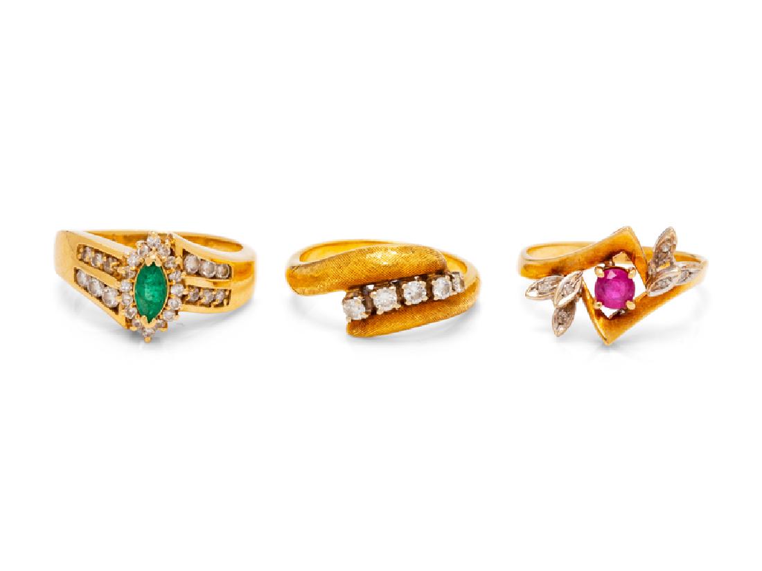 A Collection of Yellow Gold and Diamond Rings,: consisting of a 14 karat gold ring containing one round mixed cut ruby and six single cut diamonds, a 14 karat gold ring containing one marquise cut emerald and 28 round brilliant cut diamonds weighin