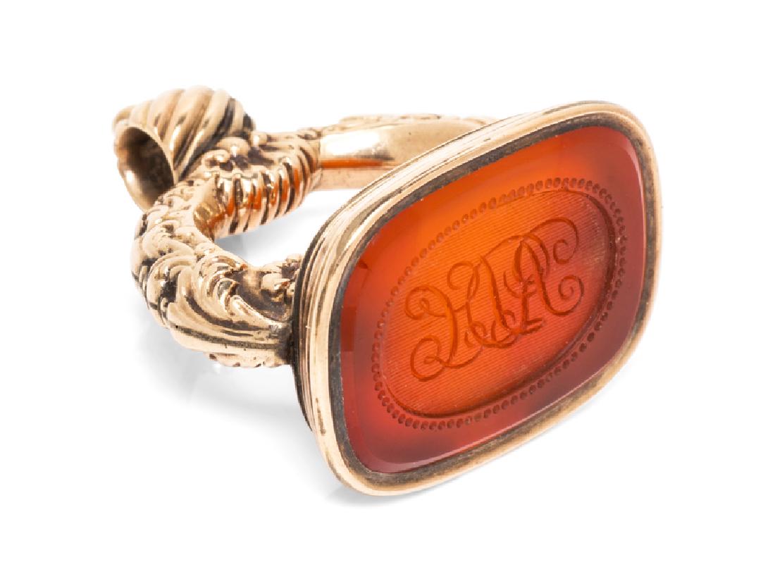 A Yellow Gold and Carnelian Fob,Â : containing one cushion shape engraved carnelian. 13.50 dwts. Provenance: Property from the Estate of Jacqueline Macomber, Fox Point, Wisconsin