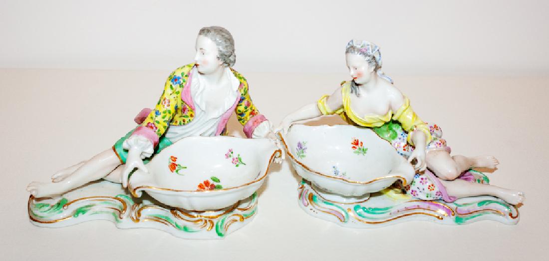 *A Pair of Meissen Porcelain Sweetmeat Stands: 19TH CENTURY Modeled as a reclining maiden and gentleman before a bowl, raised on a rocaille base; crossed swords mark in underglaze blue, impressed numerals 2872 and 2878. Height 4 1/2 x length 7 x d