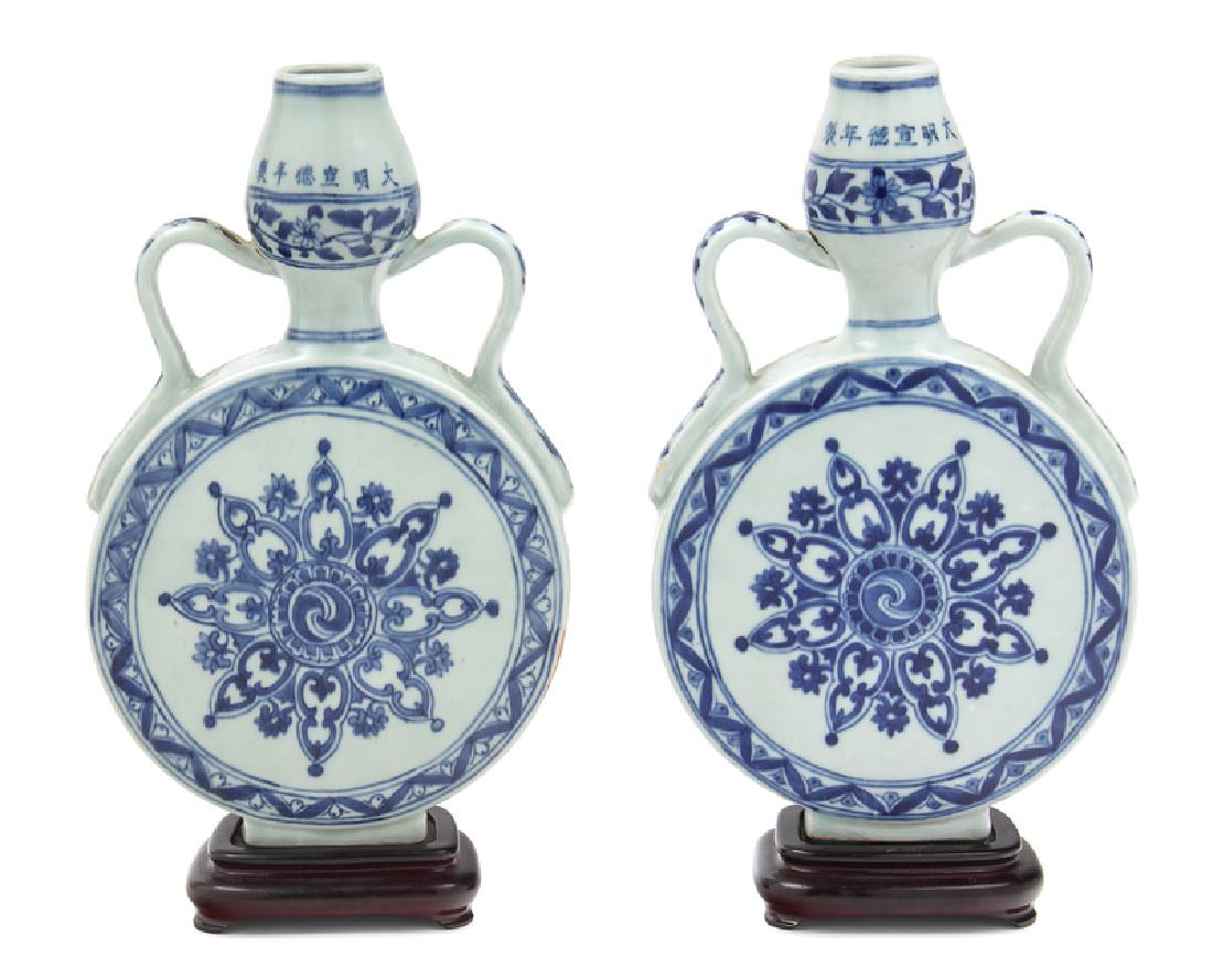 A Pair of Chinese Blue and White Porcelain Moon Flasks,: A Pair of Chinese Blue and White Porcelain Moon Flasks, Bianhu 20TH CENTURY potted with a flattened spherical body rising to a garlic neck flanked by a pair of loop handles, painted with central styli