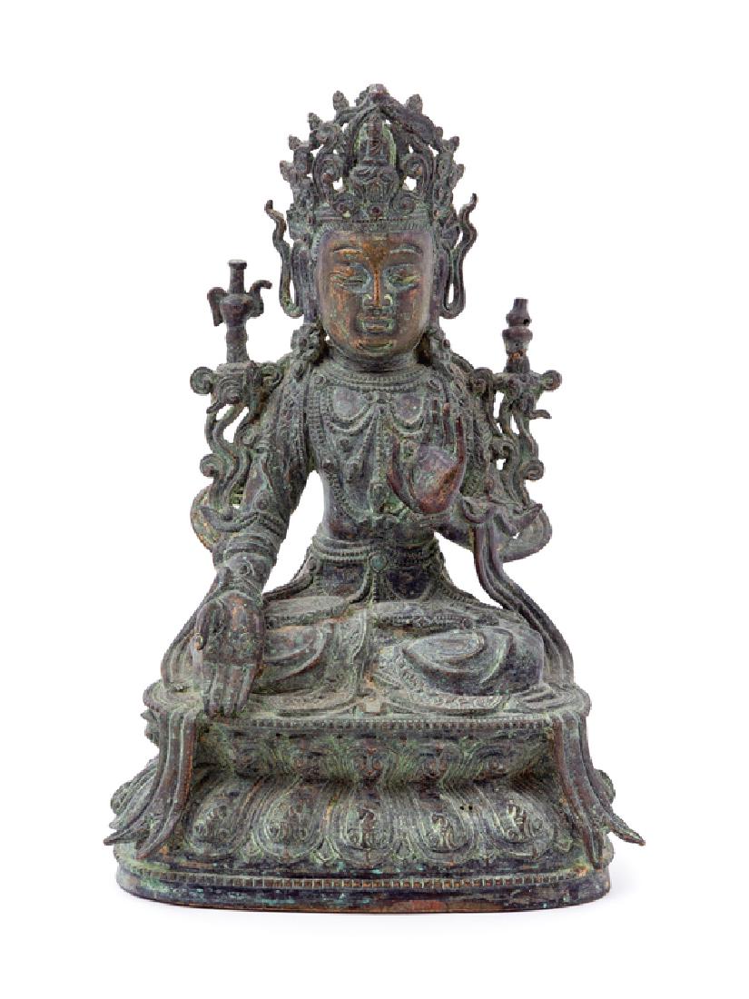 A Chinese Bronze Figure of Guanyin the deity depicted: A Chinese Bronze Figure of Guanyin the deity depicted seated on a double lotus plinth, dressed in long robes, wearing elaborate jewelry and a peaked crown, the face cast with a serene expression. 22 h