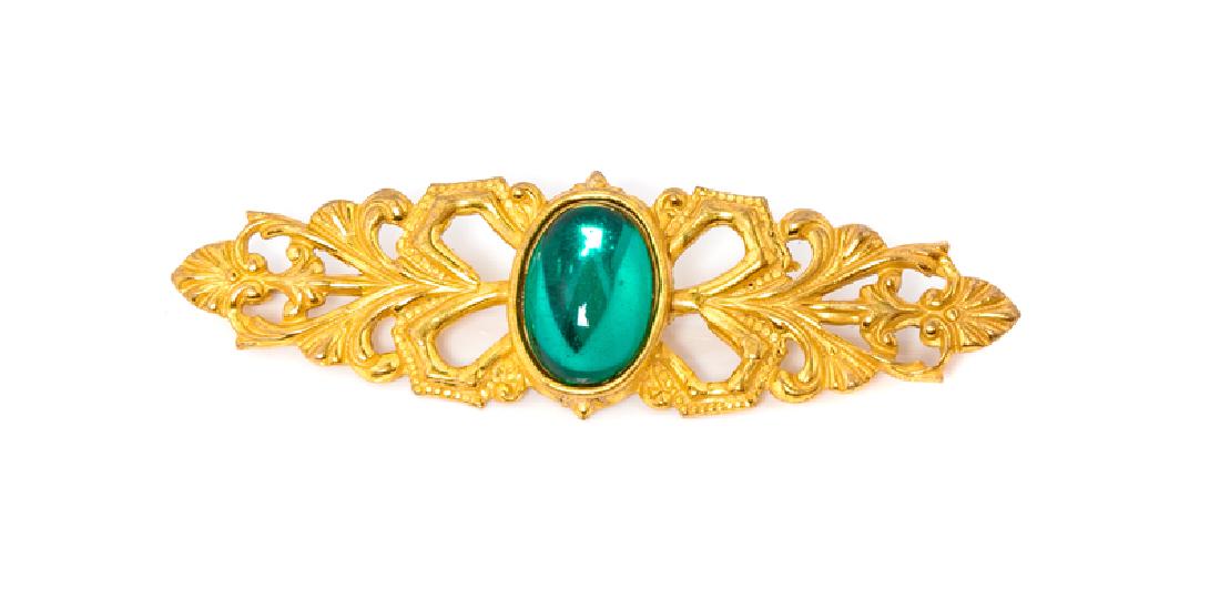 Miriam Haskell Brooch, 1970-80s: Miriam Haskell Brooch, 1970-80s Goldtone with a central green stone. Measures: 2.5" L X 0.75" H Stamped: Miriam Haskell Condition: Overall excellent condition. The stated overall condition of th