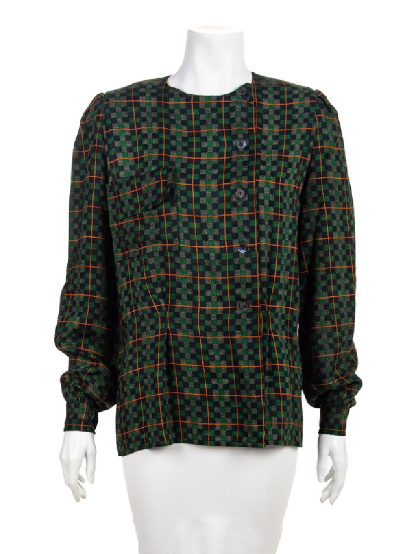 Gucci Blouse, 1970-80s: Gucci Blouse, 1970-80s Printed wool and silk blend blouse in a green, grey and orange plaid. The bodice is cut with a crew neckline, long sleeves and an off-center button closure. The right front of t