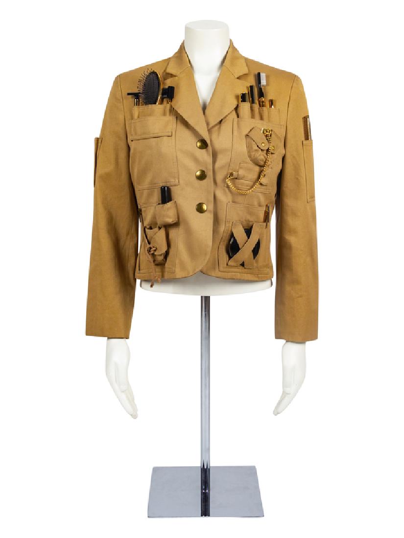 Moschino 'Survival Jacket', 1991: Moschino 'Survival Jacket', 1991 Khaki colored utility jacket detailed with pockets containing beauty accessories, including brush, empty compact, comb, empty lipstick tube, among others. Center front