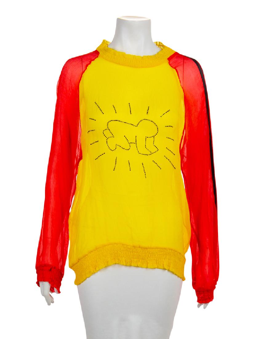 JC de Castelbajac Keith Haring's 'Radiant Child', 1990s: JC de Castelbajac Top, 1990s Yellow with red sleeves sheer silk crepe top with Keith Haring's 'Radiant Child' in blue crystals. The crew neckline, sleeve and top hems are slightly gathered. The left r