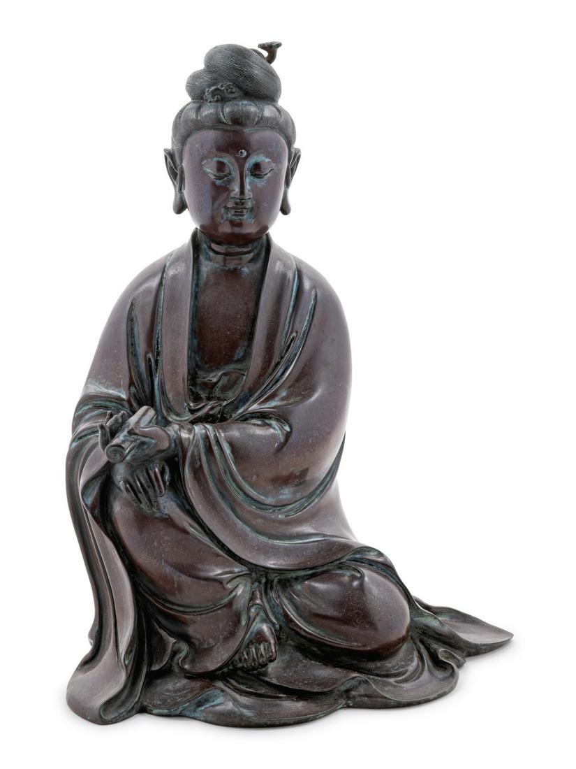 A Silver Inlaid Bronze Figure of Guanyin Height 12 1/2: A Silver Inlaid Bronze Figure of Guanyin cast seated and dressed in long flowing robes draped from the shoulders and falling over the arms and legs leaving the chest bare, holding a scroll in the left
