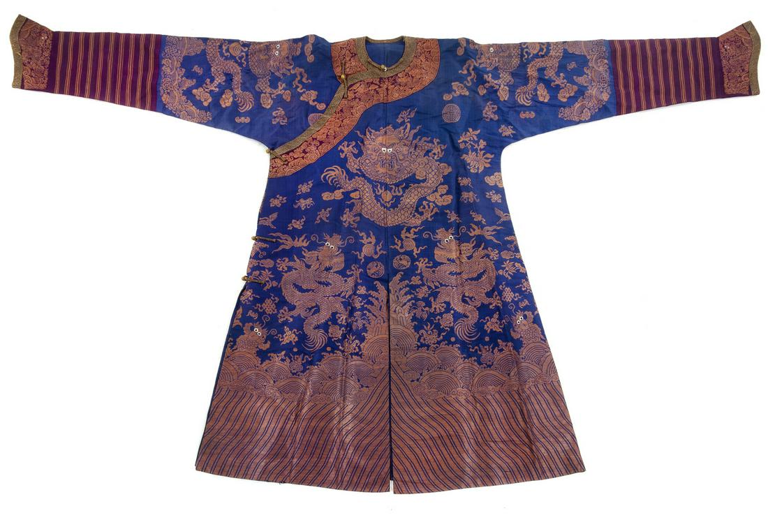 A Blue Ground Silk Dragon Robe Collar to hem: 54 1/2: A Blue Ground Silk Dragon Robe EARLY 20TH CENTURY embroidered against a blue silk ground with nine dragons, all above lishui waves supporting the bajixiang emblems, all couched with gold-wrapped silk 