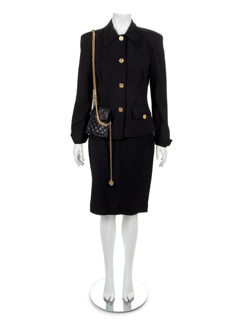 Moschino Skirt Suit, 1990s: Moschino Skirt Suit, 1990s Black jacket with black quilted bag on right hip with goldtone chain worn over left shoulder. Left faux pocket with goldtone button. Center front goldtone button closure. Fu