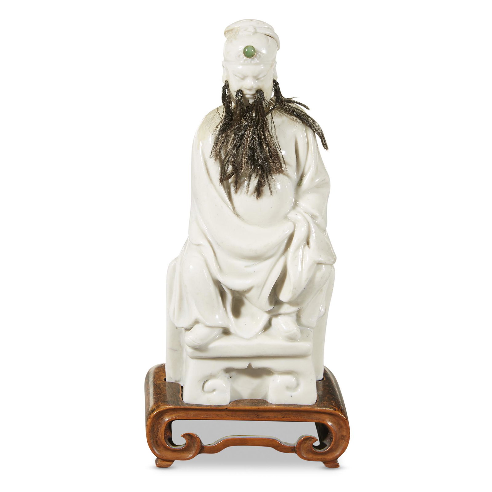 A Chinese blanc de Chine figure of seated Guandi,: A Chinese blanc de Chine figure of seated Guandi, DehuaQing dynasty, possibly 17th/18th century. Depicting the seated warrior deity with applied beard and "jewel'-inlaid headdress, fitted lacquered wo