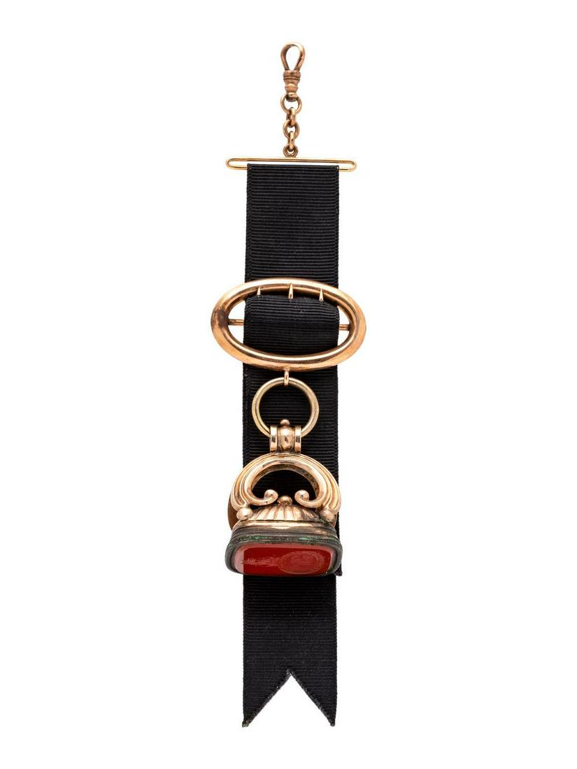 An Antique 14 Karat Rose Gold, Gold Filled and: An Antique 14 Karat Rose Gold, Gold Filled and Carnelian Fob Pendant, consisting of a 14 karat gold Albert swivel clasp and buckle with attached black ribbon suspending a gold filled fob containing 