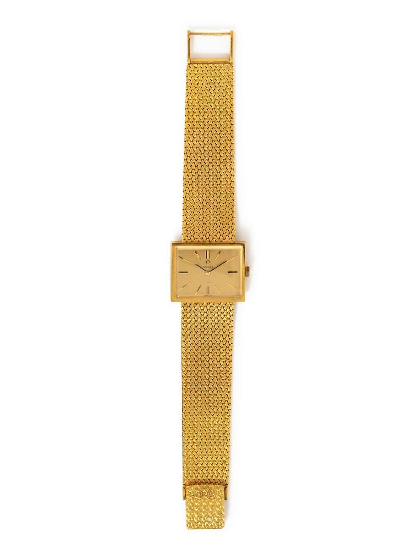 An 18 Karat Yellow Gold Wristwatch, Omega,: An 18 Karat Yellow Gold Wristwatch, Omega, 26.00 x 22.00 mm case dimensions, matte champagne dial signed OMEGA, applied gold baton numerals, black pencil hands, snap on case back, Cal. 620 17 jewel ma