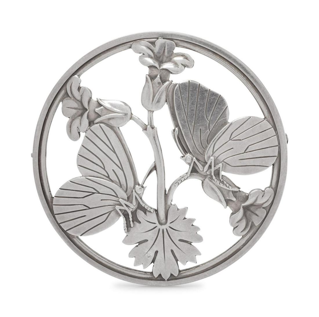 A Sterling Silver 'Moonlight Blossom' Brooch, Arno: A Sterling Silver 'Moonlight Blossom' Brooch, Arno Malinowski for Georg Jensen, consisting of a round pierced brooch with butterflies and flowers. Stamp: (maker's mark) 925 S DENMARK 283. 16.80 dwts.