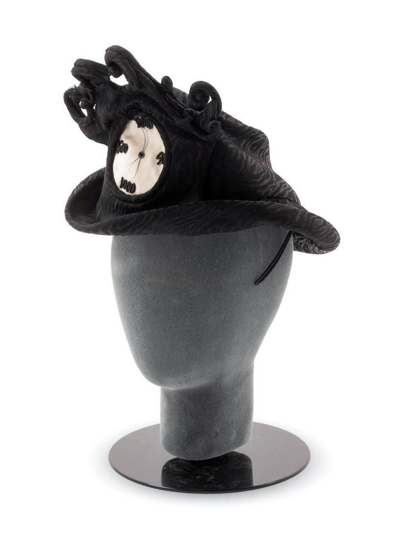 Two Stephen Jones Felt Hats, 2000s: Two Stephen Jones Felt Hats, 2000s The first is a black hat with a stylized weave shaped into a clock with both hands on '2000' in celebration of New Year's Eve. The white satin face of the hat also h