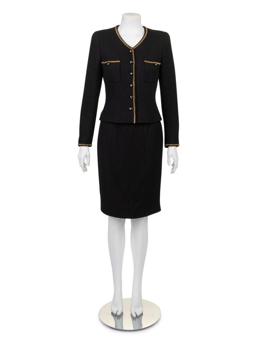 Chanel Skirt Suit, 1995: Chanel Skirt Suit, 1995 Jacket and skirt of black boucle wool. Jacket has v neck line, long sleeves, patch pockets on front, center front closure and trimmed with gold chain. Straight skirt with thin 
