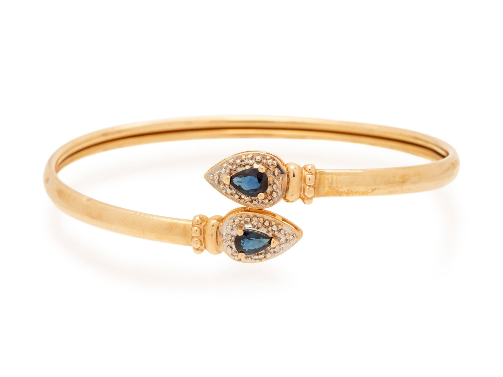 SAPPHIRE AND DIAMOND BANGLE BRACELET: SAPPHIRE AND DIAMOND BANGLE BRACELET Consisting of a flexible bypass style bangle containing two pear shape sapphires measuring approximately 5.65 x 4.00 mm and four single cut diamonds weighing appro