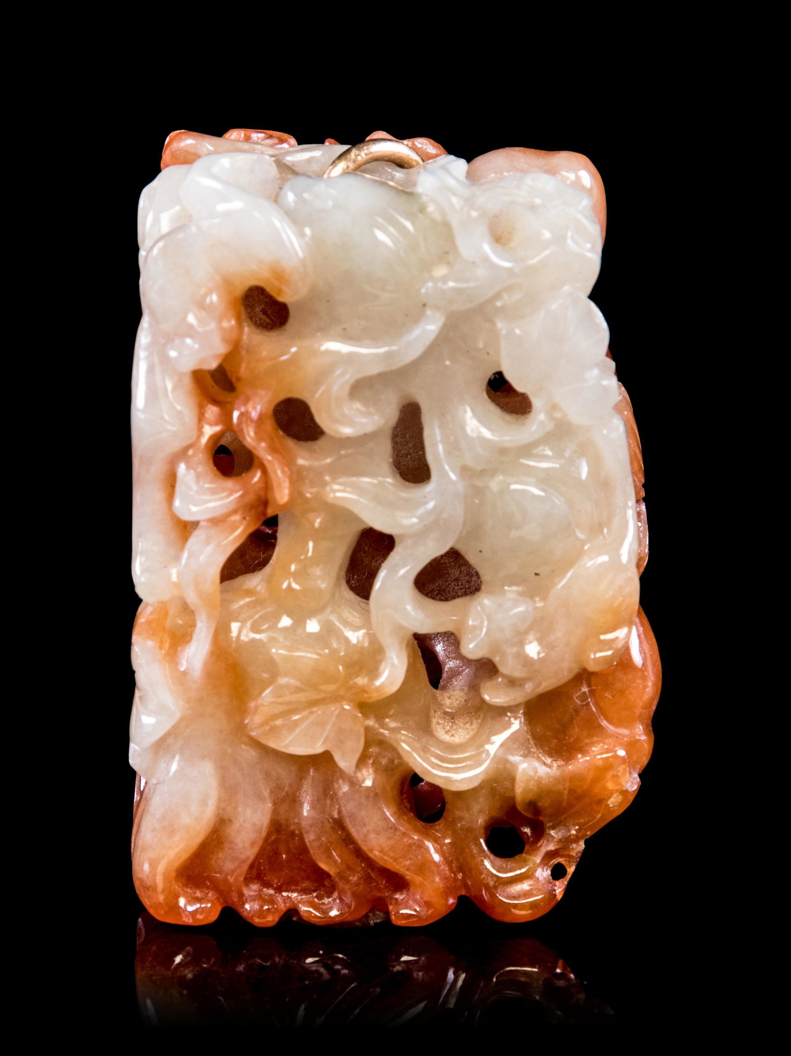 A Chinese Russet Jadeite Reticulated Pendant: A Chinese Russet Jadeite Reticulated Pendant 20TH CENTURY Length 1 3/4 in., 4 cm. reticulated with leafy vines and fruits, the stone of russet color with white patches.