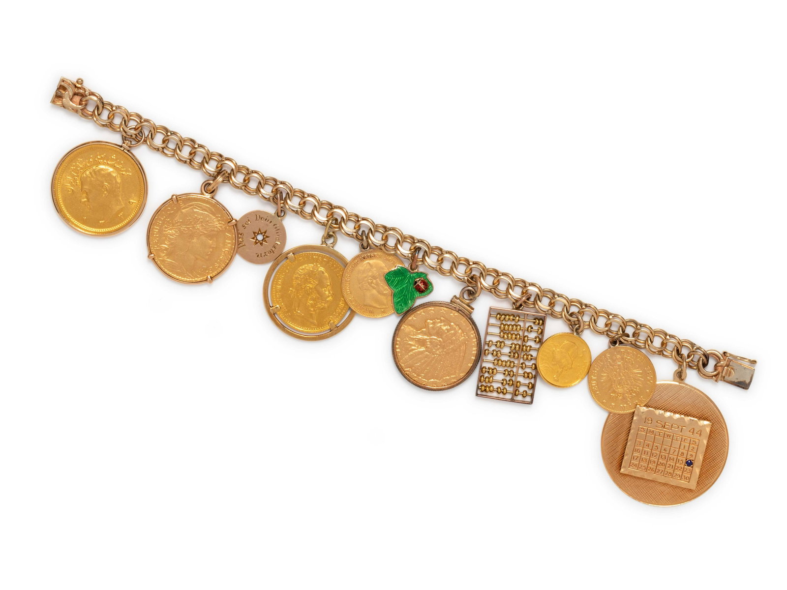 YELLOW GOLD CHARM BRACELET: YELLOW GOLD CHARM BRACELET Consisting of a fancy link bracelet suspending a calendar charm with one sapphire, a Prussian 5 mark coin charm, dated 1877, a Republic of Singapore 5 Singold coin, dated 19
