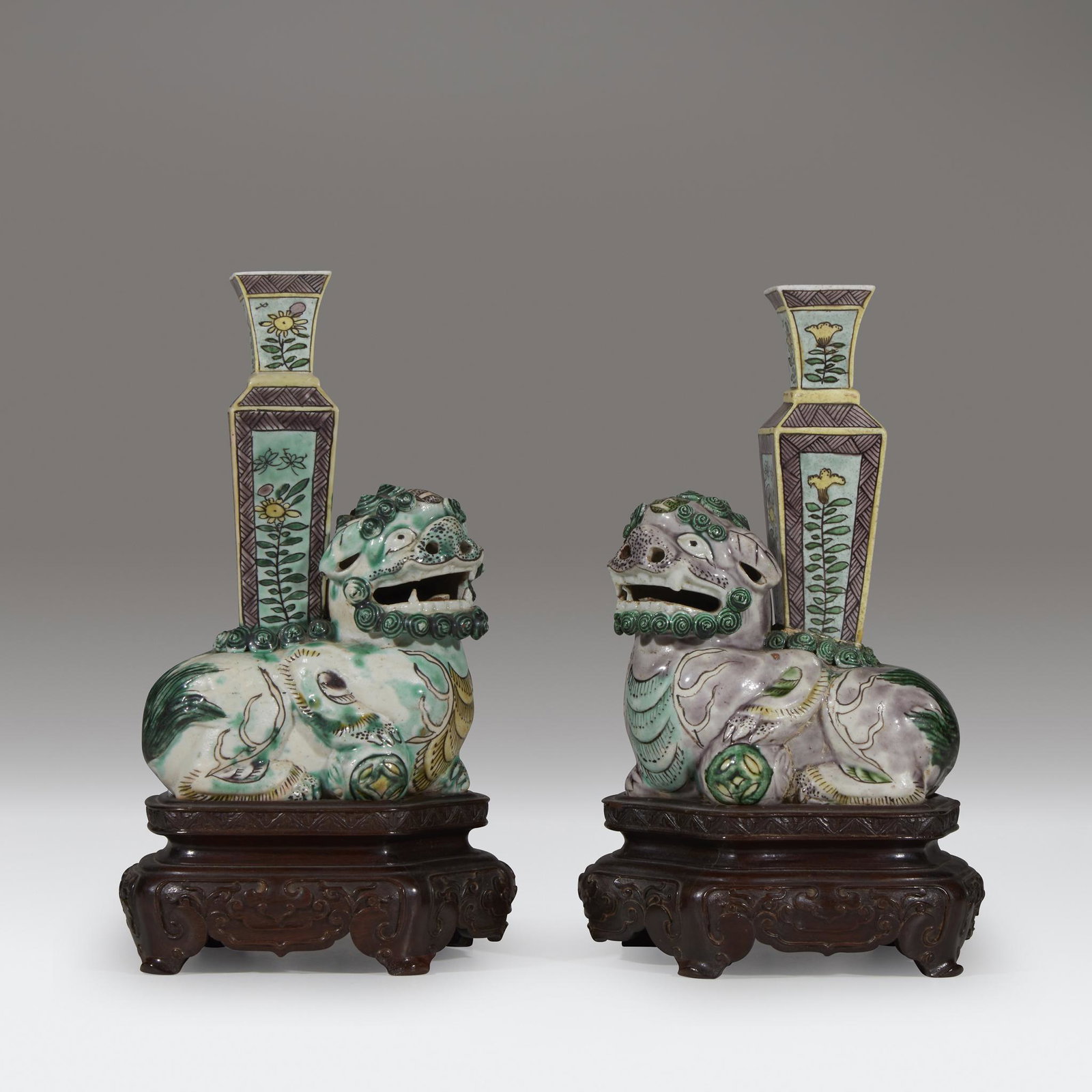 An associated pair of small Chinese famille verte: An associated pair of small Chinese famille verte "Buddhist Lion" joss stick holdersKangxi periodOne with a purple glaze to body; the other with a deep green glaze, each depicted recumbant with a broc