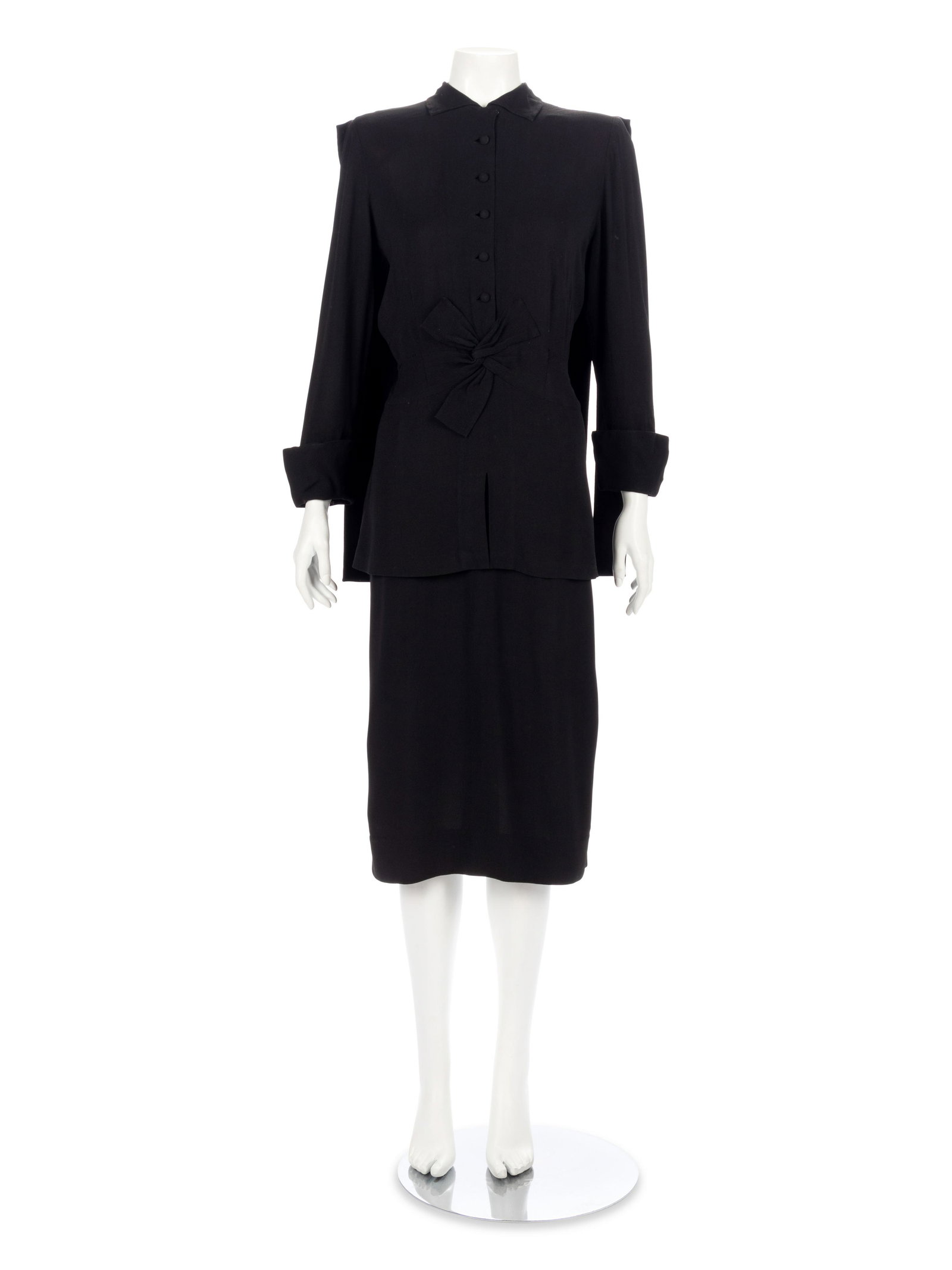 Adrian Black Dress, 1940s: Adrian Black Dress, 1940s Black silk crepe long sleeve dress with roll collar, front waist knot detail with peplum over straight fit skirt, center front button closure, and back self fabric strip "cap
