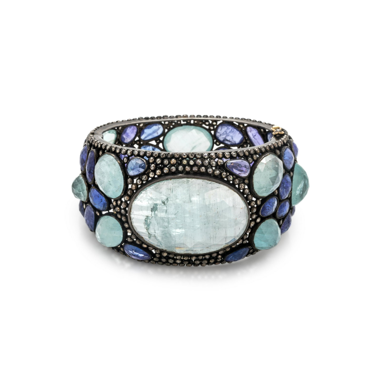 TOURMALINE, TANZANITE AND DIAMOND BANGLE BRACELET: TOURMALINE, TANZANITE AND DIAMOND BANGLE BRACELET Containing one oval rose cut tourmaline measuring approximately 36.00 x 25.00 mm, nine tourmalines and 32 tanzanites in various shapes and sizes and n