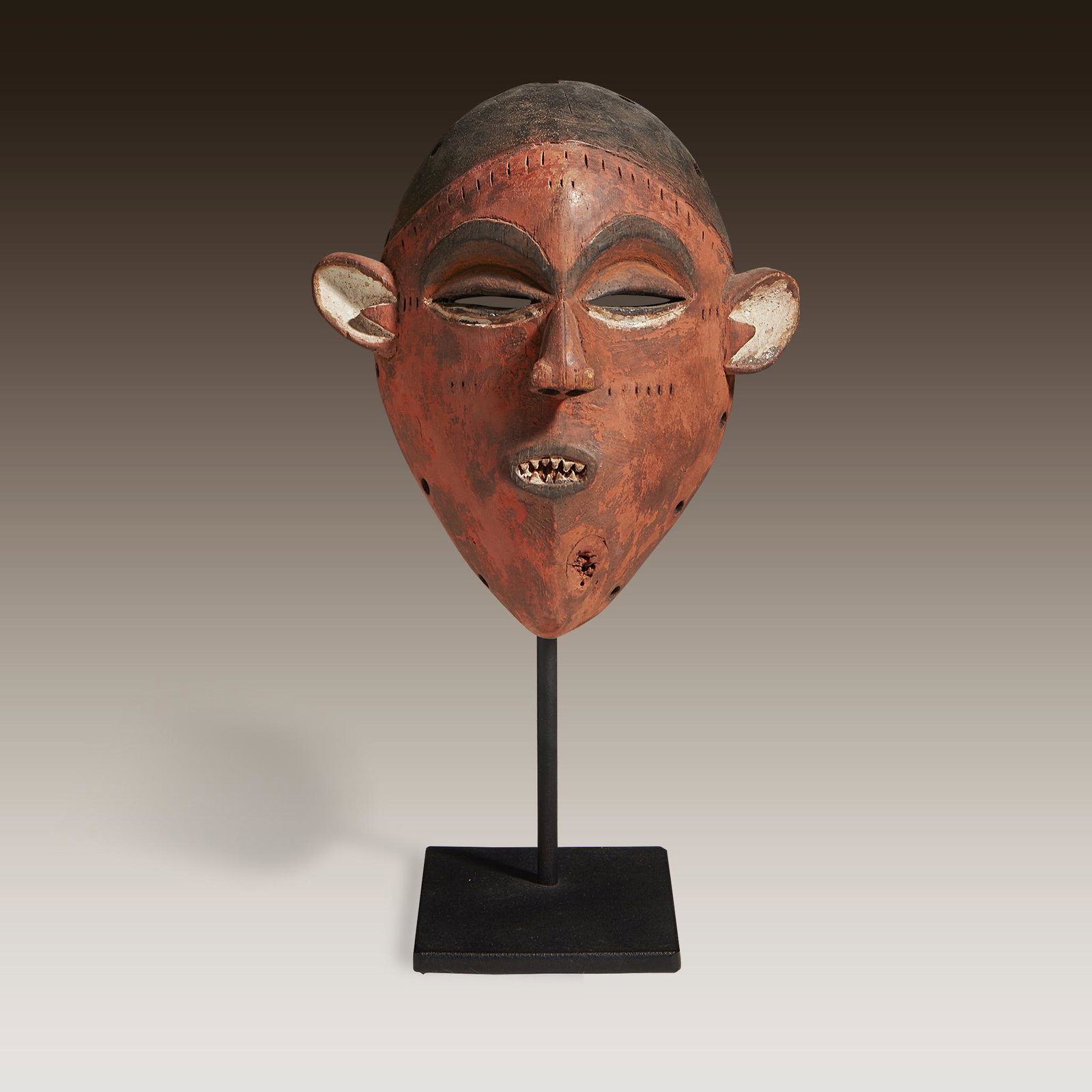A Pende mask, Democratic Republic of Congo: A Pende mask Democratic Republic of Congo Carved wood and pigment, of fearsome appearance, the perforated eyes below arching brows, the aquiline nose above an open mouth exposing rows of jagged teeth,