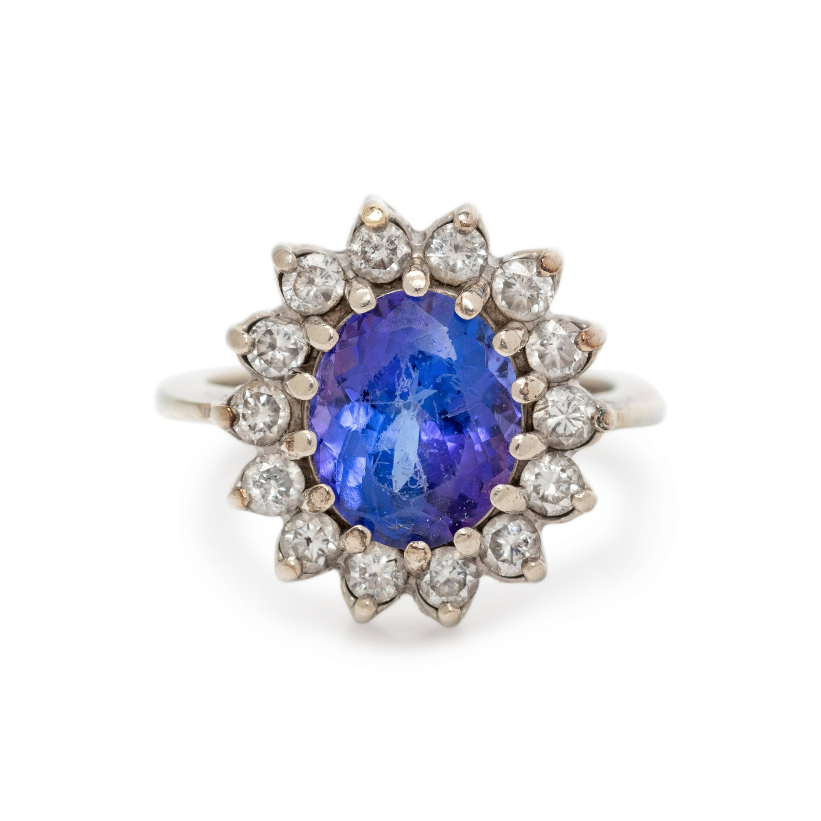 TANZANITE AND DIAMOND RING: TANZANITE AND DIAMOND RING Containing one oval mixed cut tanzanite measuring approximately 10.90 x 9.30 x 6.00 mm and 14 round brilliant cut diamonds weighing approximately 0.90 carat total. Mounted i