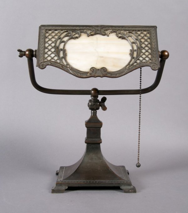 A Handel Desk Lamp, Height 12 1/4 inches.: A Handel Desk Lamp, the triangular shade set with glass and pierced metal decoration, having adjustable shade and raised over a square footed base. Height 12 1/4 inches.