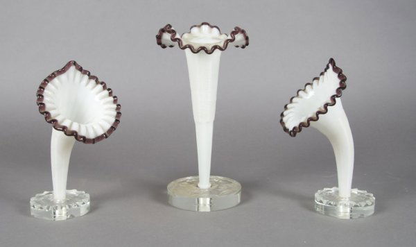 A Victorian Three Piece Garniture Set, Height of t: A Victorian Three Piece Garniture Set, each glass trumpet with ruffled rim set in a circular, engraved base. Height of tallest 10 3/4 inches.