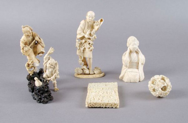 A Collection of Japanese Ivory Articles, Height of: A Collection of Japanese Ivory Articles, comprising a seated robed woman, a gentleman with frogs, a gentleman playing music, a demon, a puzzle ball, and a card case. Height of first 4 1/4 inches.