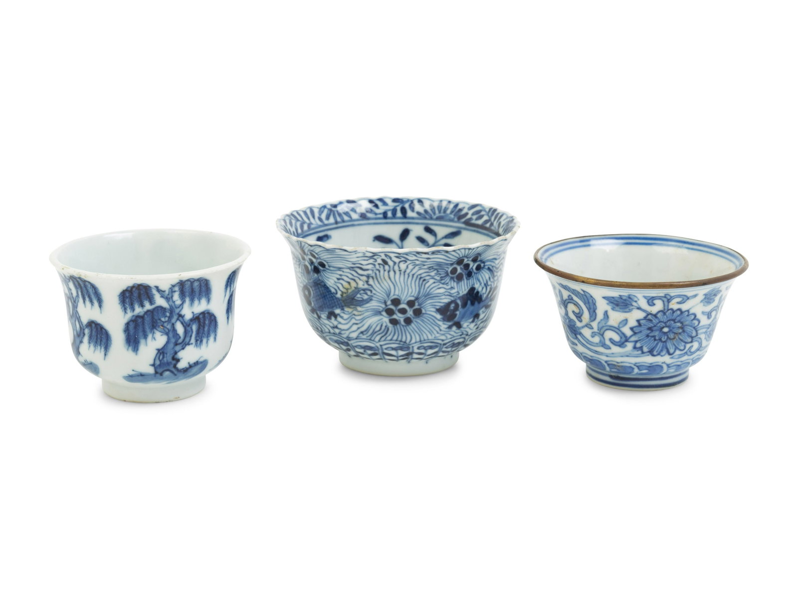 Three Chinese Blue and White Porcelain Wine Cups: Three Chinese Blue and White Porcelain Wine Cups KANGXI PERIOD (1654-1722) the first painted with willow trees, the second of flori-form and decorated with fishes, the third with copper mounted mouth,