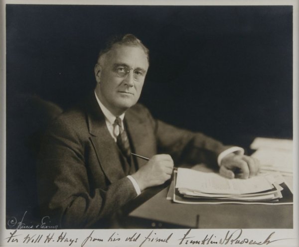 ROOSEVELT, FRANKLIN DELANO. Signed photograph.: ROOSEVELT, FRANKLIN DELANO Signed photograph of FDR at a desk with a stack of papers. Inscribed in the lower border to Will Hays, "For Will H. Hays from his old friend Franklin D. Roosevelt." Undated,